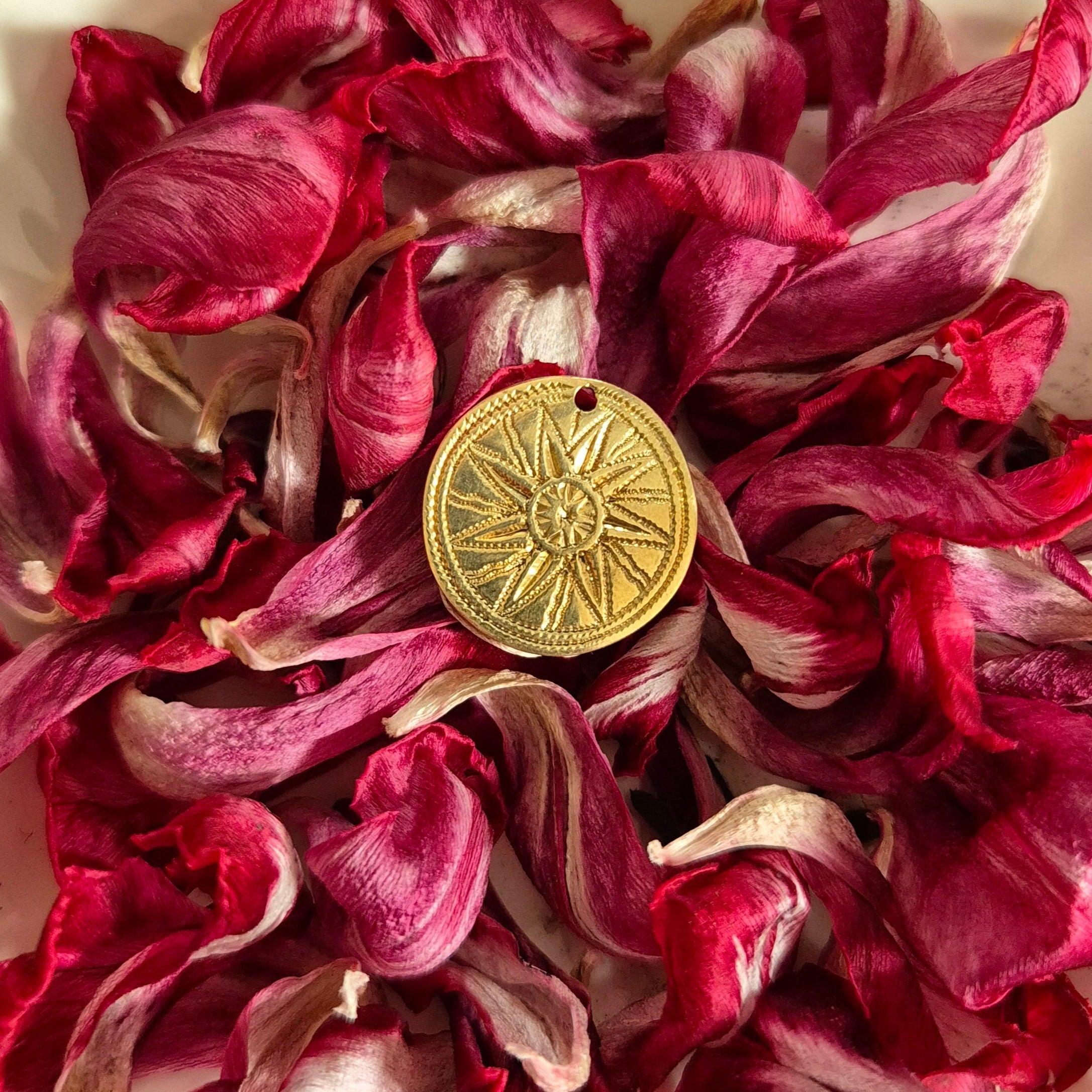 zoom médaille soleil bronze posée dans fleurs fushia